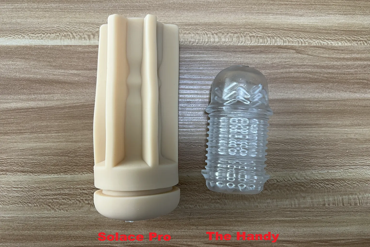 Comparación de la funda de TPE beige del Lovense Solace Pro con la funda transparente de The Handy, mostrando las diferencias de longitud, tamaño y diseño